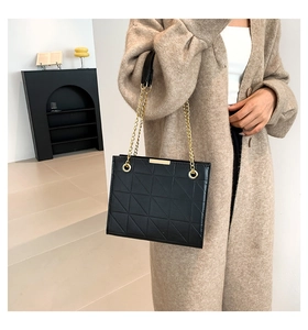 Gros plan du sac à bandoulière noir matelassé avec chaîne dorée et motifs géométriques