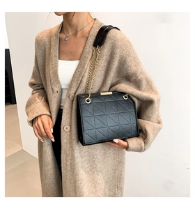 Détail du sac à bandoulière noir matelassé avec chaîne dorée et texture en cuir de luxe