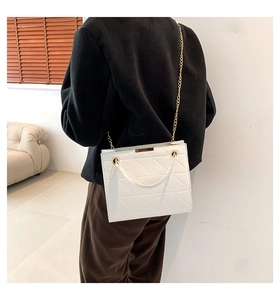 Détail du sac bandoulière matelassé blanc avec chaîne dorée porté à l'épaule