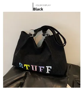 Close-up of black corduroy tote bag with colorful STUFF embroidery and silver metal rings