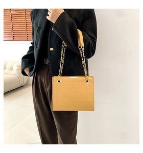 Détail du sac matelassé géométrique jaune avec chaîne dorée et bandoulière en cuir
