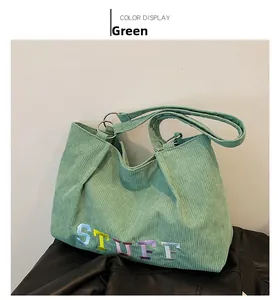 Detail of green corduroy tote bag with colorful STUFF embroidery and metal ring