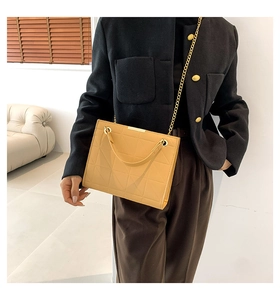 Détail du sac matelassé jaune gingembre avec chaîne en métal porté par un mannequin