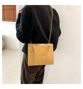 Gros plan du petit sac cabas matelassé jaune moutarde avec bandoulière chaîne dorée sur modèle