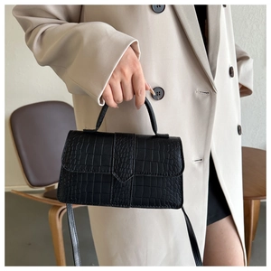 Gros plan du sac à main noir à motif crocodile avec poignée et bandoulière amovible