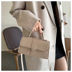 Détail de la texture crocodile beige et du rabat en V sur ce petit sac carré