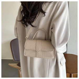 Détail de la texture cuir crocodile beige clair sur un sac bandoulière élégant