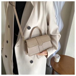 Détail de la texture crocodile abricot sur un sac à bandoulière chic avec sangle en cuir