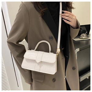 Sac à main blanc à motif crocodile avec garniture dorée porté par un mannequin femme