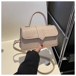 Détail de la texture motif crocodile beige et de la poignée sur un petit sac carré