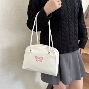 Minimalist white shell bag with pink butterfly embroidery on a black knit sweater model