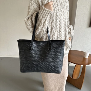 Chic black woven tote bag with slim shoulder straps shown on a model for daily commute