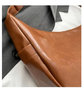 Close-up detail of the brown pebble leather texture and stitching on this saddle shoulder bag