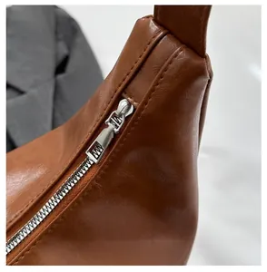 Detail of a brown leather dumpling bag showing lychee texture and silver metal zipper