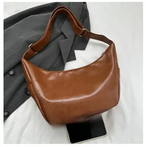Detail of brown PU leather dumpling bag with lychee texture and adjustable shoulder strap
