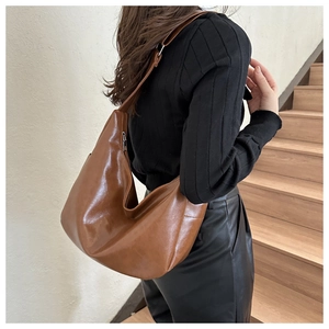 Detail of a brown leather hobo shoulder bag with silver hardware and adjustable strap