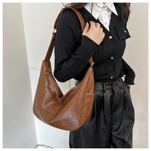 Brown leather hobo bag worn by model, showing large capacity and soft texture