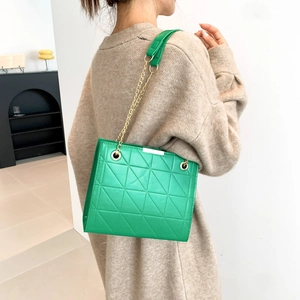 Sac fourre-tout matelassé vert vif avec chaîne dorée porté par un mannequin