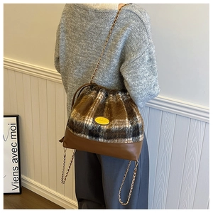 Detail of wool plaid bucket bag with gold chain strap and elegant drawstring closure