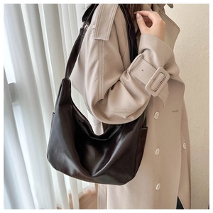 Brown vintage faux leather hobo bag for women worn by a model in a beige trench coat