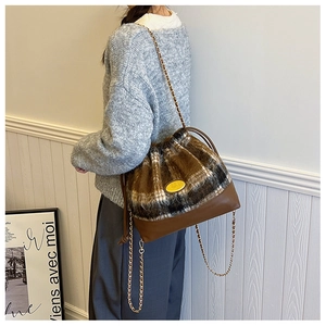 Close-up of a plaid wool bucket bag with gold chain strap and drawstring closure