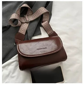Close-up of retro brown crossbody bag with wide jacquard strap and size comparison to phone