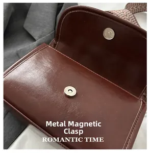 Detail of the magnetic snap closure and vintage woven strap on the brown crossbody bag