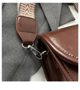 Detail of dark brown leather bag with multi-color herringbone woven strap and silver hooks