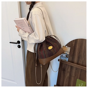 Detail of vintage wool plaid bucket bag featuring leather patchwork and golden chain strap