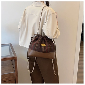Detail of vintage drawstring bucket bag with brown plaid fabric and gold chain strap