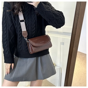 Brown leather crossbody square bag with wide geometric pattern strap on a female model