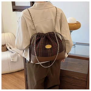 Detail of vintage brown plaid wool bucket bag with gold chain strap and drawstring closure