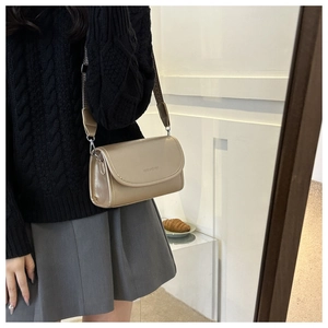 Detail of champagne gold square bag featuring fashion & bags embossed text and wide strap