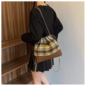 Detail of vintage plaid bucket bag with gold chain strap and drawstring closure