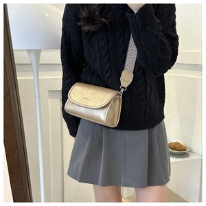 Champagne gold leather crossbody bag with patterned wide strap shown on model