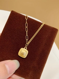 Dettaglio di collana vintage dorata con pendente quadrato goffrato su fondo di velluto