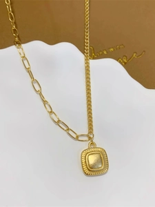 Dettaglio di collana dorata con catena a graffetta asimmetrica e ciondolo quadro vintage