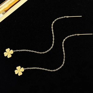 Eleganti orecchini a quadrifoglio dorati con catene lunghe su sfondo nero raffinato