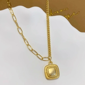 Collana asimmetrica dorata con ciondolo quadrato arrotondato su vassoio bianco