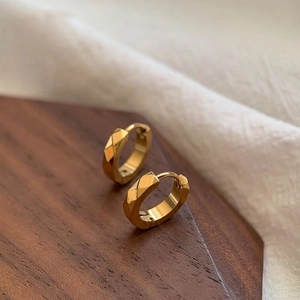 Créoles dorées minimalistes avec motif géométrique en diamant sur support bois
