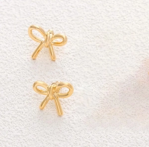 Detailed view of 3D golden bow stud earrings with a polished metallic mirror finish