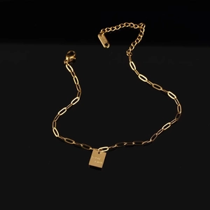 Elegant gold titanium steel anklet with Good Luck square tag on black mirror background