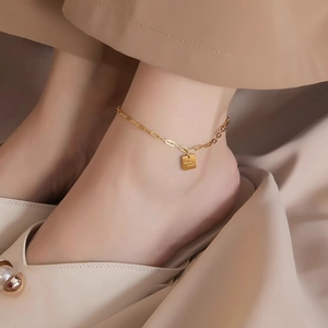 Golden titanium steel anklet with square Good Luck charm on a female ankle