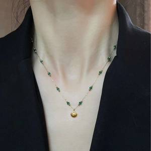 Vintage emerald beaded necklace with gold shell pendant on elegant woman collarbone