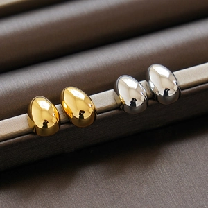 Vue macro des boucles d'oreilles boules dorées et argentées dans une boîte en soie
