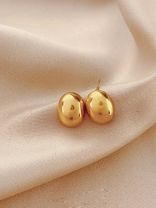 Boucles d'oreilles haricots en or poli sur un tissu en soie élégant avec ombres