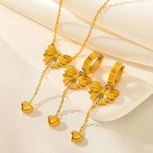 Ensemble bijoux dorés avec nœud et pendentif cœur sur fond de soie élégante