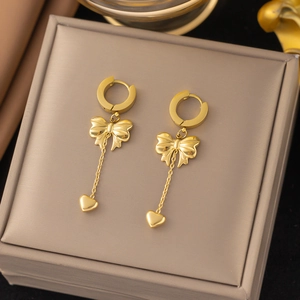 Élégantes boucles d'oreilles nœud doré avec pendentif cœur sur boîte à bijoux
