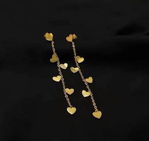 Gros plan sur les boucles d'oreilles cœur dorées avec longues chaînes sur tissu noir