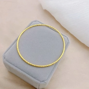 Polished 18K gold plated titanium bangle with sparkling hammered texture on velvet box